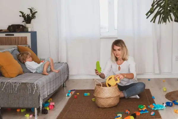 Filip leży na kanapie, a mama, która chyba zapomniała o porządku, siedzi na dywanie wśród zabawek.