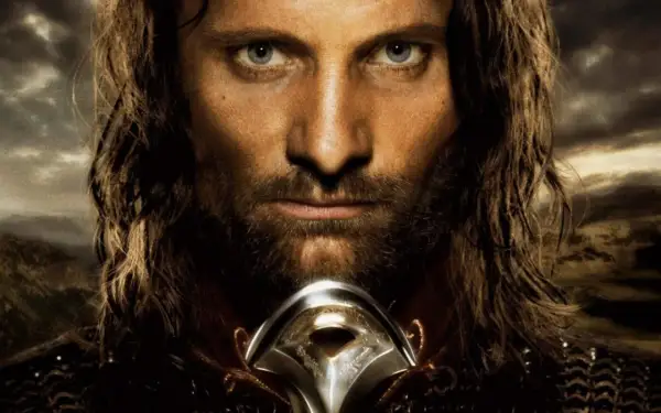 Viggo Mortensen jako Aragorn, zamyślony, z mieczem u szyi, na tle burzowego nieba i gór.