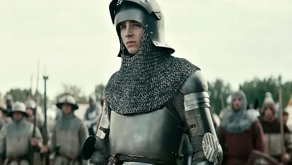 Młody rycerz w zbroi, gotowy do bitwy. Scena z filmów o średniowieczu, gdzie historia ożywa na ekranie.