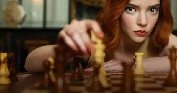 Beth Harmon, bohaterka "Gambitu królowej 2", skupiona na szachownicy, wykonuje ruch.